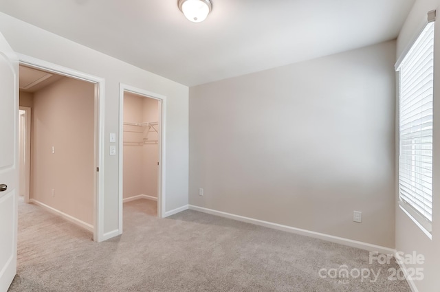 unfurnished bedroom with a walk in closet, light colored carpet, and a closet