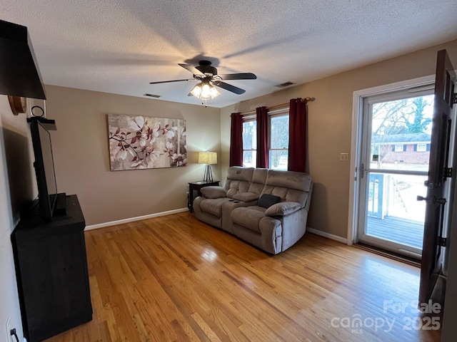 living room featuring ceiling fan, a textured ceiling, and light hardwood / wood-style flooring