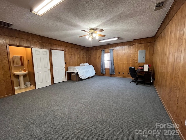 unfurnished bedroom with sink, wooden walls, electric panel, carpet floors, and a textured ceiling