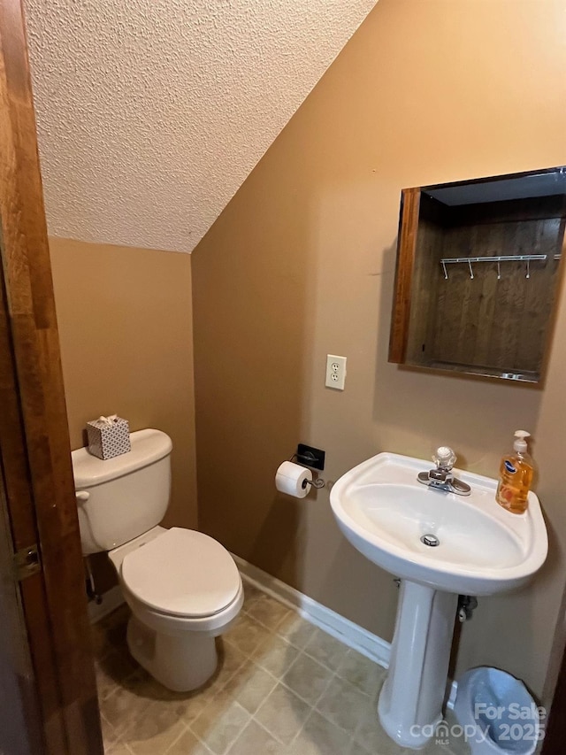 bathroom featuring a textured ceiling, vaulted ceiling, and toilet