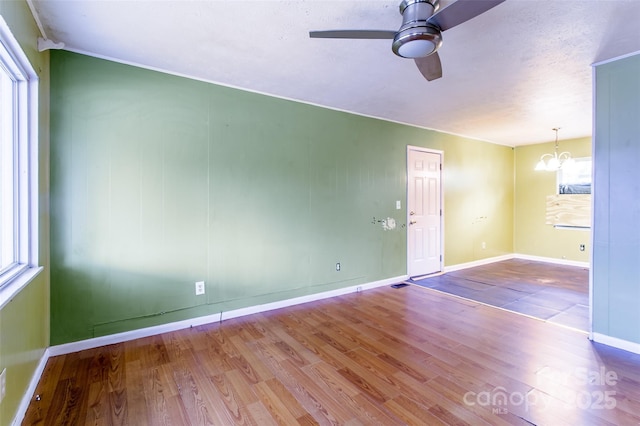 empty room featuring ceiling fan with notable chandelier and light hardwood / wood-style flooring