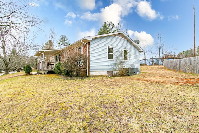 view of side of property with a deck, central air condition unit, and a lawn