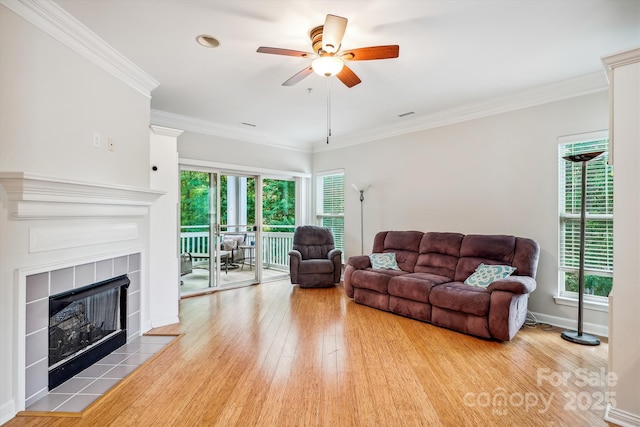 living area featuring ornamental molding, a wealth of natural light, a fireplace, and wood finished floors