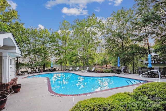 pool with a patio area and fence