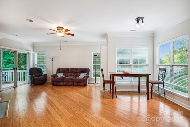 living room featuring light wood-type flooring, a wealth of natural light, baseboards, and crown molding