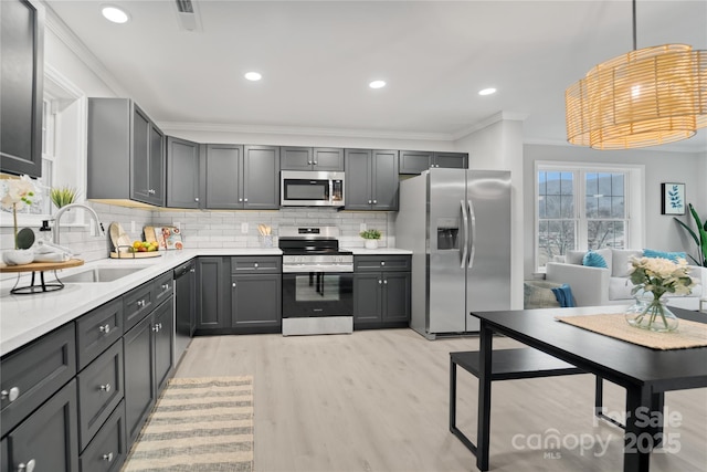 kitchen with stainless steel appliances, gray cabinets, sink, and hanging light fixtures