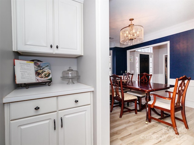 dining room featuring ornamental molding, light wood-style flooring, and a notable chandelier