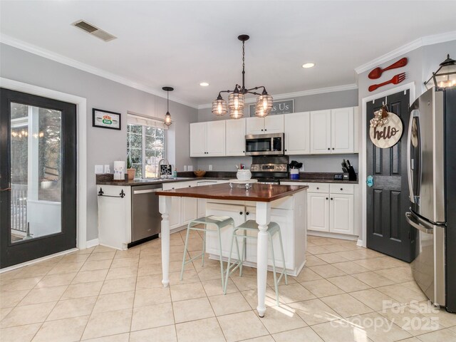 kitchen with visible vents, white cabinets, decorative light fixtures, a center island, and stainless steel appliances