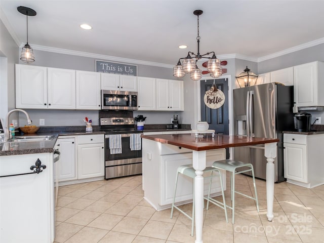 kitchen with stainless steel appliances, hanging light fixtures, a sink, and white cabinets