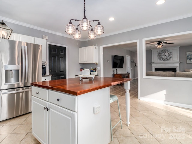 kitchen with butcher block counters, open floor plan, light tile patterned flooring, white cabinetry, and stainless steel fridge