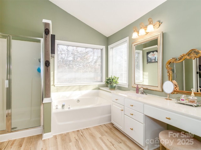 full bathroom with double vanity, lofted ceiling, a stall shower, wood finished floors, and a bath