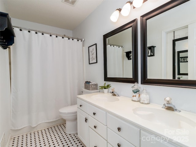 bathroom featuring toilet, double vanity, a sink, and visible vents