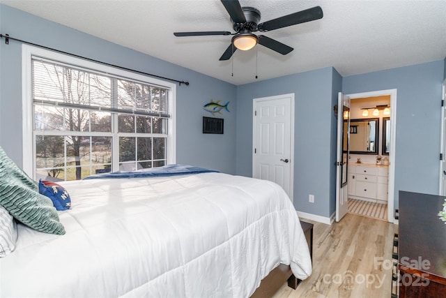 bedroom with a textured ceiling, ensuite bathroom, light wood-style flooring, and baseboards