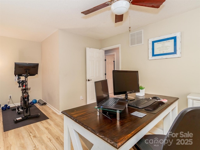 office space with light wood-type flooring, visible vents, ceiling fan, and baseboards