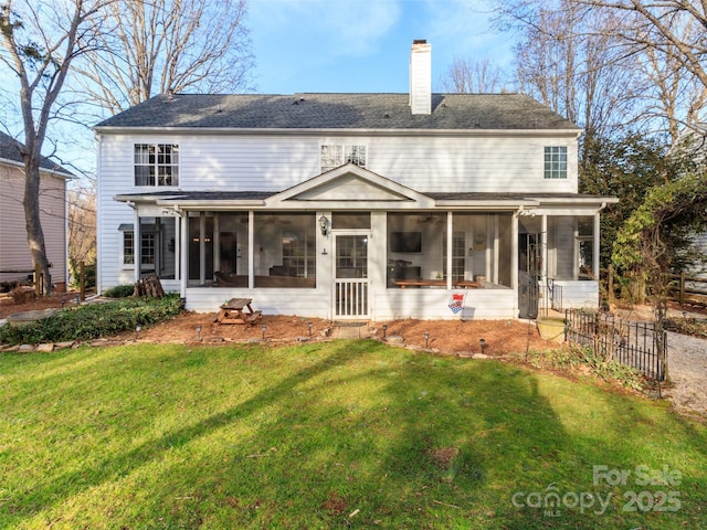 back of property with a lawn, a chimney, fence, and a sunroom