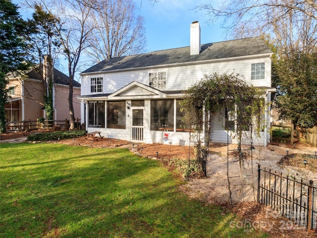 rear view of property featuring a sunroom, a chimney, fence, and a lawn