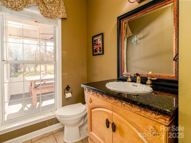 half bath with vanity, toilet, and tile patterned floors