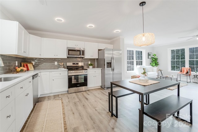 kitchen with crown molding, hanging light fixtures, stainless steel appliances, tasteful backsplash, and white cabinets