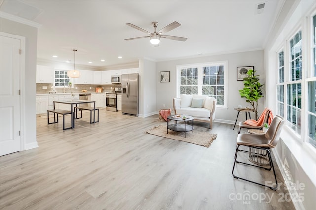 living room featuring crown molding, ceiling fan, and light hardwood / wood-style floors