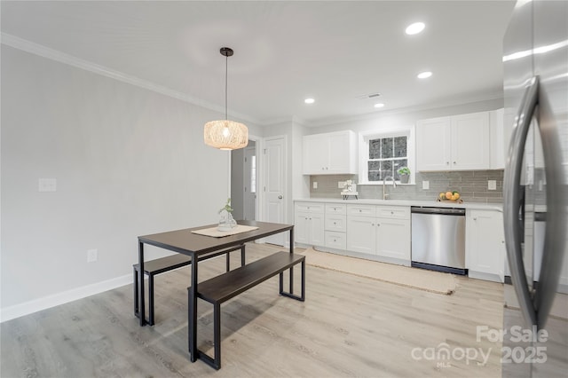 kitchen with crown molding, stainless steel appliances, hanging light fixtures, and white cabinets