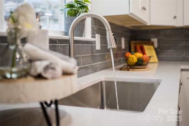 details with backsplash, sink, and white cabinets