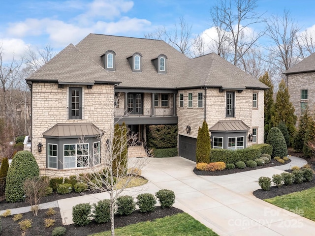 view of front of home with driveway, a standing seam roof, an attached garage, a shingled roof, and stone siding