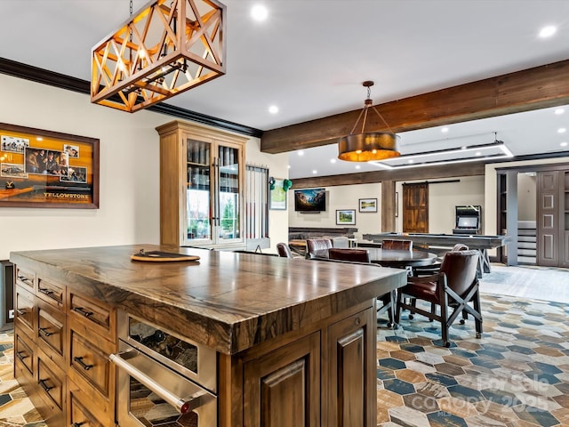 kitchen featuring wooden counters, beamed ceiling, open floor plan, ornamental molding, and stainless steel oven