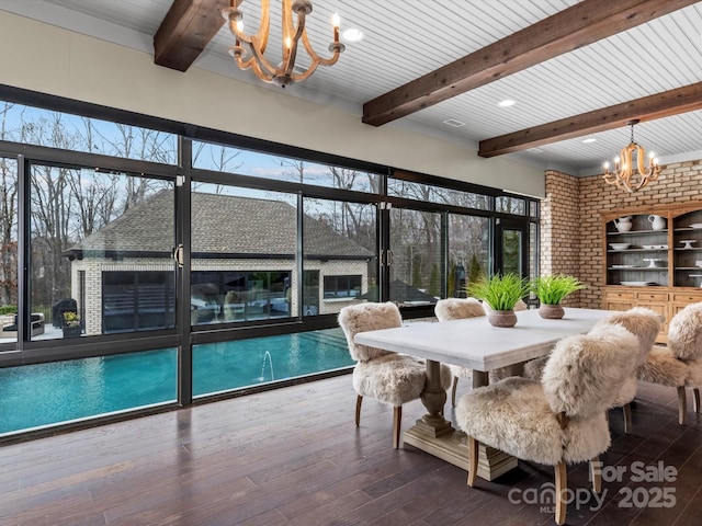 dining room featuring a chandelier, beamed ceiling, brick wall, and wood-type flooring