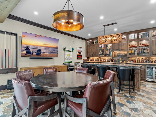 dining area with stone finish flooring, crown molding, beverage cooler, recessed lighting, and wet bar