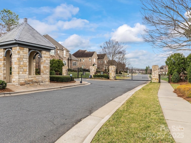 view of road with a gate, curbs, sidewalks, and a gated entry