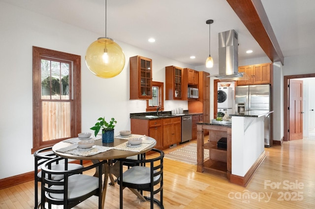 kitchen with island range hood, stainless steel appliances, decorative light fixtures, and stacked washer / drying machine