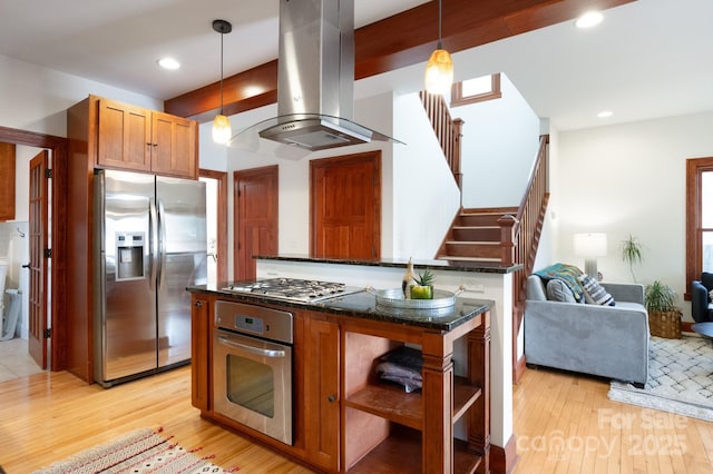 kitchen with appliances with stainless steel finishes, dark stone countertops, hanging light fixtures, island exhaust hood, and light wood-type flooring