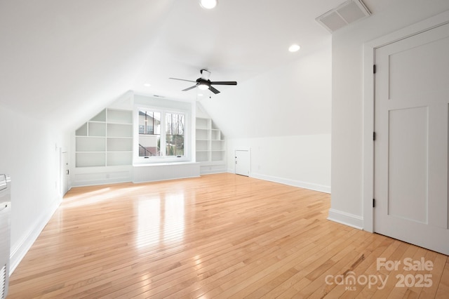 additional living space with vaulted ceiling, ceiling fan, built in features, and light wood-type flooring