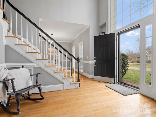 foyer entrance with crown molding, light hardwood / wood-style flooring, and a towering ceiling