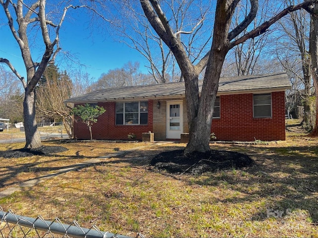 ranch-style home with brick siding, fence, and a front lawn