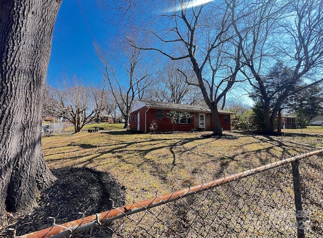 exterior space with brick siding, a front yard, and fence