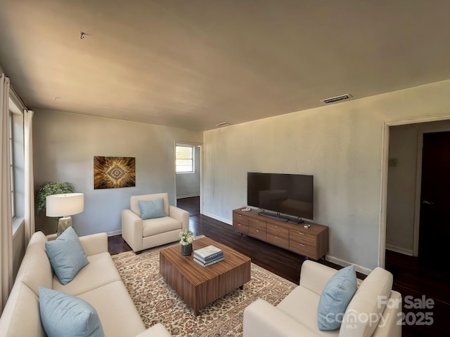 living area with wood finished floors, visible vents, and baseboards