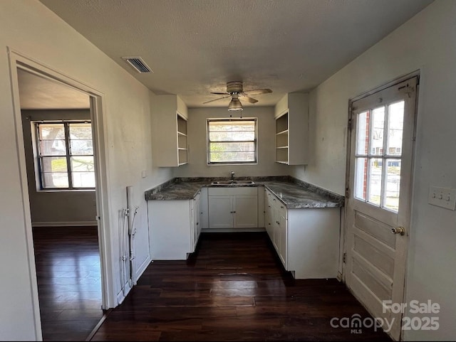 kitchen with dark countertops, visible vents, white cabinetry, and open shelves