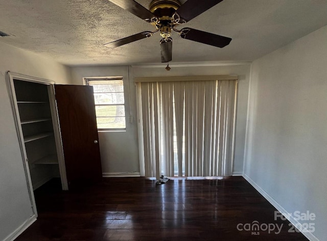 empty room with baseboards, dark wood finished floors, and a textured ceiling