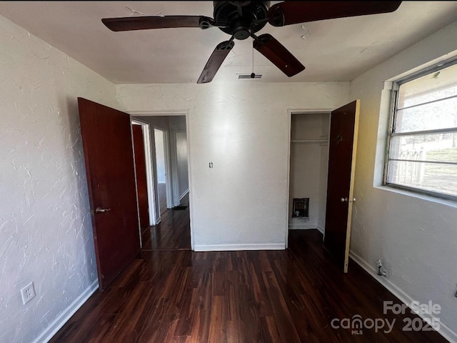 unfurnished bedroom featuring a textured wall, dark wood finished floors, visible vents, and baseboards