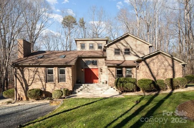 split level home with brick siding, a front lawn, and a chimney