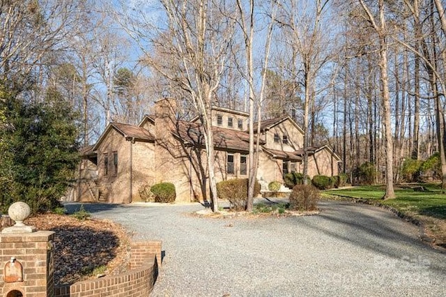 view of front facade featuring gravel driveway and a chimney