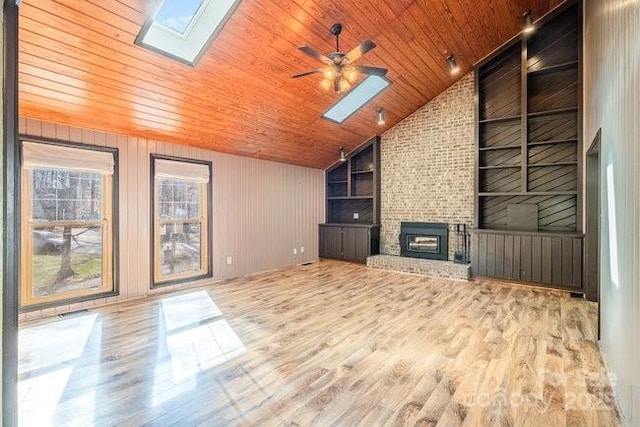 unfurnished living room with vaulted ceiling with skylight, a fireplace, wood finished floors, wood ceiling, and built in features