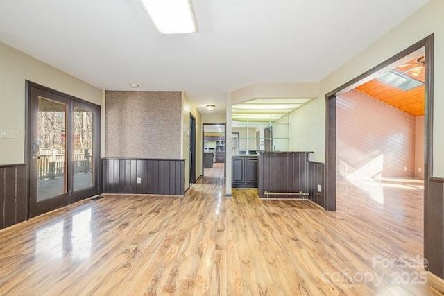 unfurnished room with light wood-style floors and wainscoting