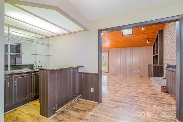 bar featuring light wood-style floors, wet bar, and wood walls