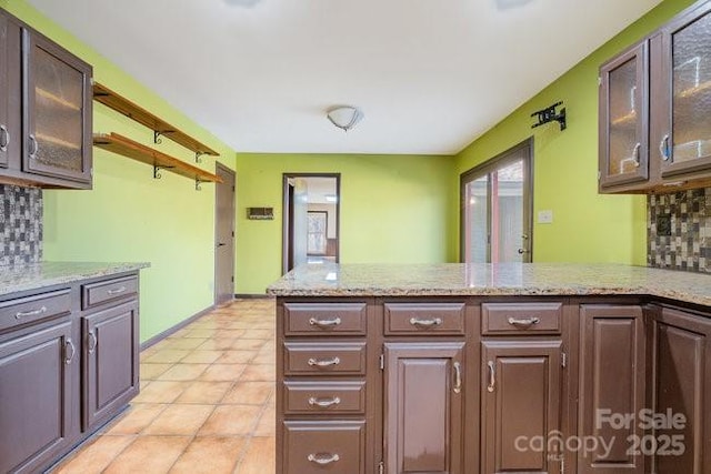 kitchen with glass insert cabinets, dark brown cabinetry, a peninsula, and tasteful backsplash