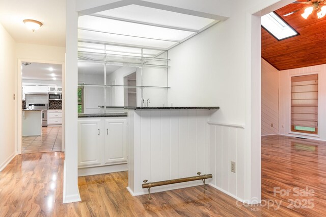 1006 Lost Cv, Weddington, NC 28104 - bar with stainless steel microwave, range, light wood-type flooring, wainscoting, and a skylight