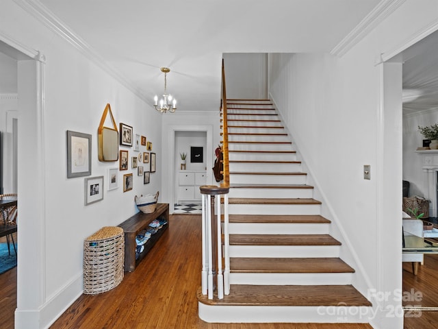 stairs with hardwood / wood-style flooring, crown molding, and a chandelier