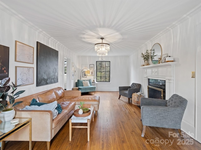 living room featuring wood-type flooring, a notable chandelier, and crown molding