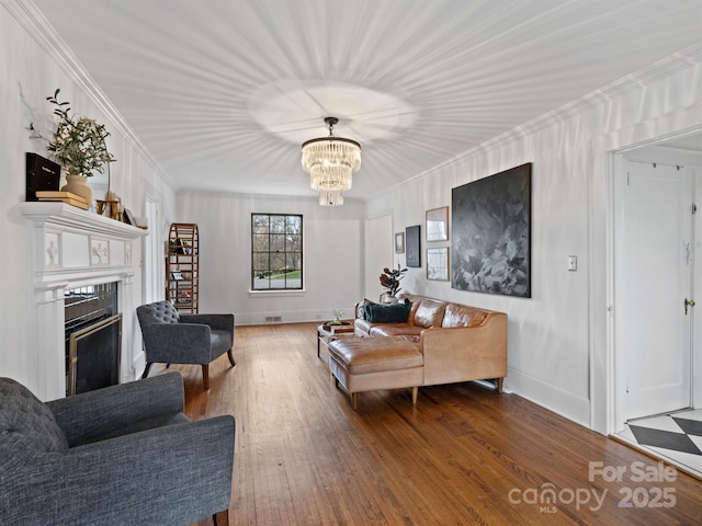 living room with crown molding, hardwood / wood-style flooring, and an inviting chandelier